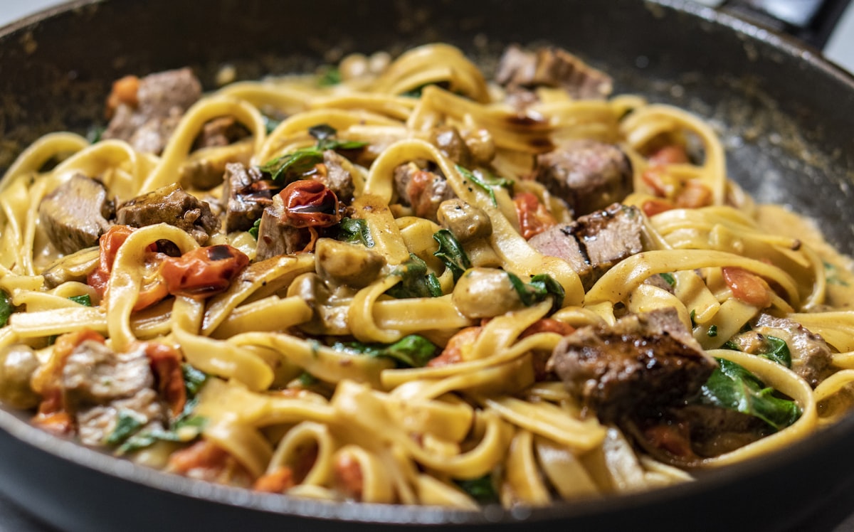 A bowl of pasta with herbs and a soft-boiled egg, photographed from above